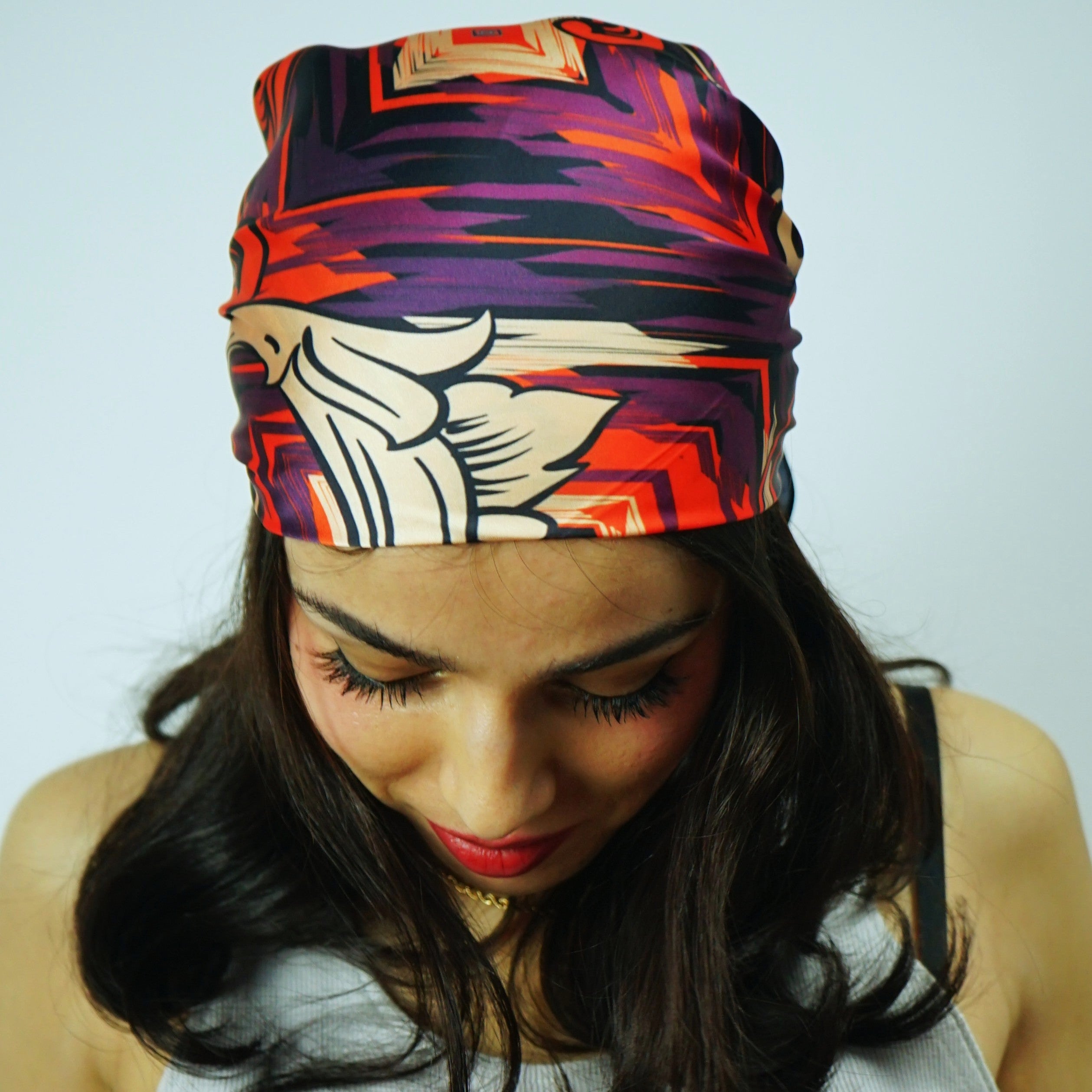 Woman wearing a colorful headscarf with a white tank top featuring 'TOYOS' branding.