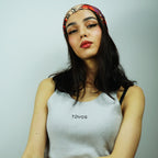 Woman wearing a white tank top with 'TOYOS' branding against a plain background